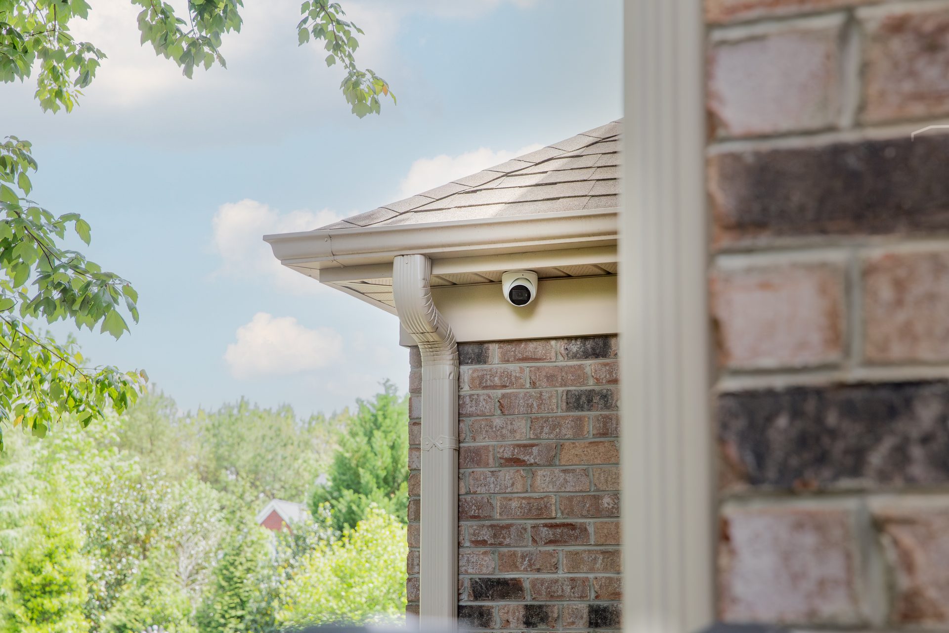 Discreet exterior camera on a well-designed facade, paired with a phone showing a live multi-camera view.